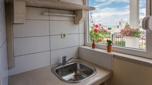 A kitchen with a stainless steel sink, white tiled backsplash, and a window with potted plants. - Villa Suzy Lux- Villa with Private Pool (Sutivan)