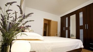 Une chambre à coucher avec un lit, une lampe de chevet, un vase de fleurs et une armoire.
