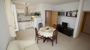 Un espace de vie compact comprenant un coin repas, une kitchenette et un téléviseur.