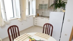 Un coin repas avec une table ronde, des chaises et une décoration centrale composée de fruits et d’herbes aromatiques.