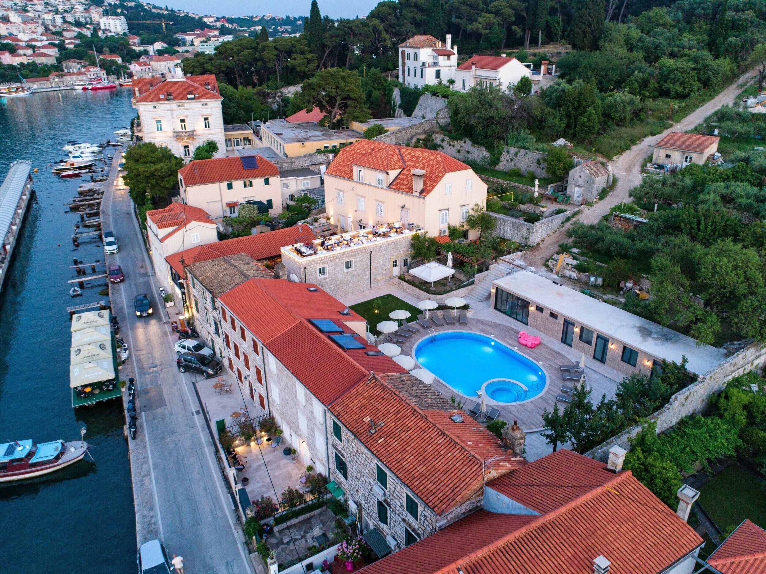 Un hotel sul lungomare con piscina, balconi a terrazza e un porto turistico.