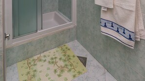 A shower with a glass door, a towel rack with two towels, and a green mat on the floor. - Apartments Kisic - Two-Bedroom Apartment with Terrace(prizemlje) (Mlini)
