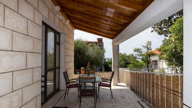 A covered patio with a stone floor, a table with chairs, and a view of the surrounding area. - Apartments Kisic - Two-Bedroom Apartment with Terrace(prizemlje) (Mlini)