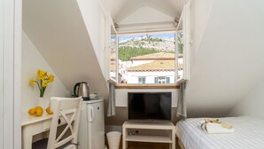 A compact room with a bed, a small desk, a television, and a window offering a view of buildings and greenery. - Guest House Lumin - Deluxe Single Room with City View (Fourth Floor) (BR5) (Dubrovnik)