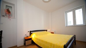A bedroom with a bed, bedside table, lamp, and a window. - Apartments Briest - Studio Apartment with Balcony (Dubrovnik)