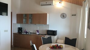 A compact kitchen with wooden cabinets, a microwave, a kettle, and a dining table with chairs. - Apartments Eastern Paradise- Comfort One Bedroom Apartment with Terrace and Sea View (Bol)