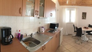 A kitchen with a sink, coffee maker, kettle, and microwave. There is a dining area with a table and chairs. - Apartments Eastern Paradise- Comfort One Bedroom Apartment with Terrace and Sea View (Bol)