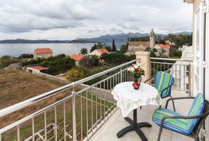 Enjoy a romantic meal on the balcony with a view of the serene body of water, church, and distant mountains.