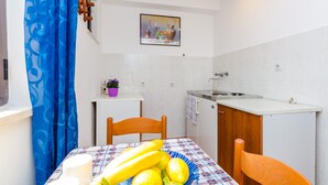A compact kitchen with a dining table, chairs, and a small countertop. - Apartments & Rooms Mihajica- Comfort Studio Apartment with Balcony and Sea View (Cavtat)