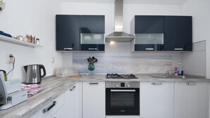 Une cuisine moderne avec des meubles blancs, un four Bosch, une cuisinière à gaz et une hotte en acier inoxydable.