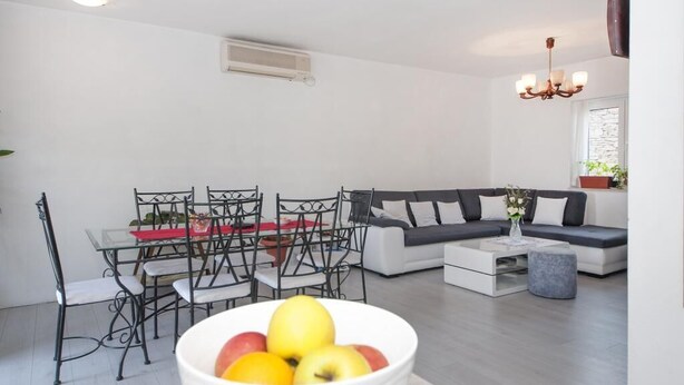 Un salon moderne avec un canapé, une table à manger, des chaises et un saladier rempli de fruits.