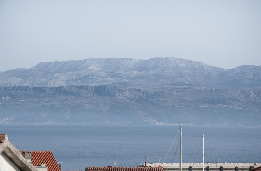 Eine Küstenansicht mit Bergen im Hintergrund und einem Steg, der ins Meer führt.