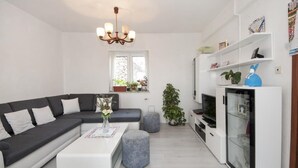 Un salon moderne avec un canapé d’angle, une table basse, un téléviseur et un meuble vitré.