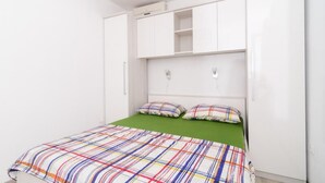 Ein Schlafzimmer mit einer grünen Bettdecke, einem weißen Kleiderschrank und einer Deckenleuchte.
