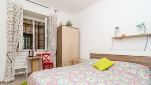 Une chambre à coucher comprenant un lit, un bureau, une chaise, une armoire et une fenêtre avec des rideaux.