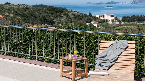 A balcony with a wooden table, a towel, and a glass of orange juice.