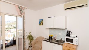 A compact kitchen with a microwave, sink, and a potted plant.