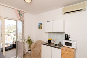 A compact kitchen with a microwave, sink, and a view through the door.