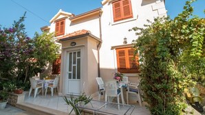 A two-story building with a balcony, a satellite dish, and a patio with chairs and a table. - Apartments Longo - Standard One Bedroom Apartment with Terrace(A3) (Supetar)