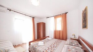Une chambre avec deux lits, une armoire et une table de chevet avec une lampe.