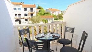 Ein Balkon mit rundem Tisch und vier Stühlen, mit Blick auf eine Wohngegend mit Häusern und Bäumen.