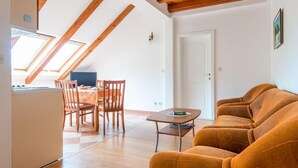 Una sala de estar moderna con techo de madera, un sofá, una mesa de comedor con sillas y una zona de cocina.