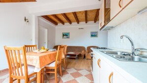 Una cocina compacta con armarios de madera, una mesa de comedor con sillas, un sofá y un lavabo.
