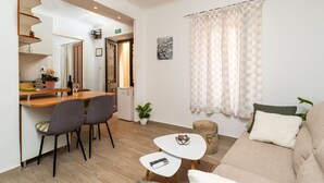 A modern living room with a sofa, a small coffee table, and a dining area with chairs and a table.