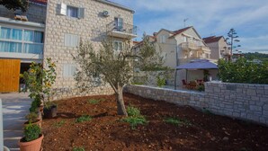 Una zona residencial con edificios de piedra, un árbol y un patio con mobiliario exterior.