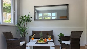 Ein Zimmer mit zwei Korbstühlen, einem weißen Tisch und einem großen Spiegel an der Wand.
