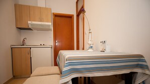 A small, compact room with a bed, bedside tables, a wooden cabinet, and a kitchenette area. - Apartments Briest (Dubrovnik)