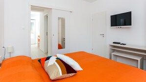 Ein Hotelzimmer mit einem großen Bett, einem an der Wand befestigten Fernseher und einer Tür zu einem Flur.