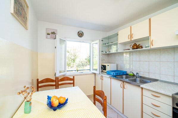 A kitchen with a dining table, chairs, a window, and cabinets.