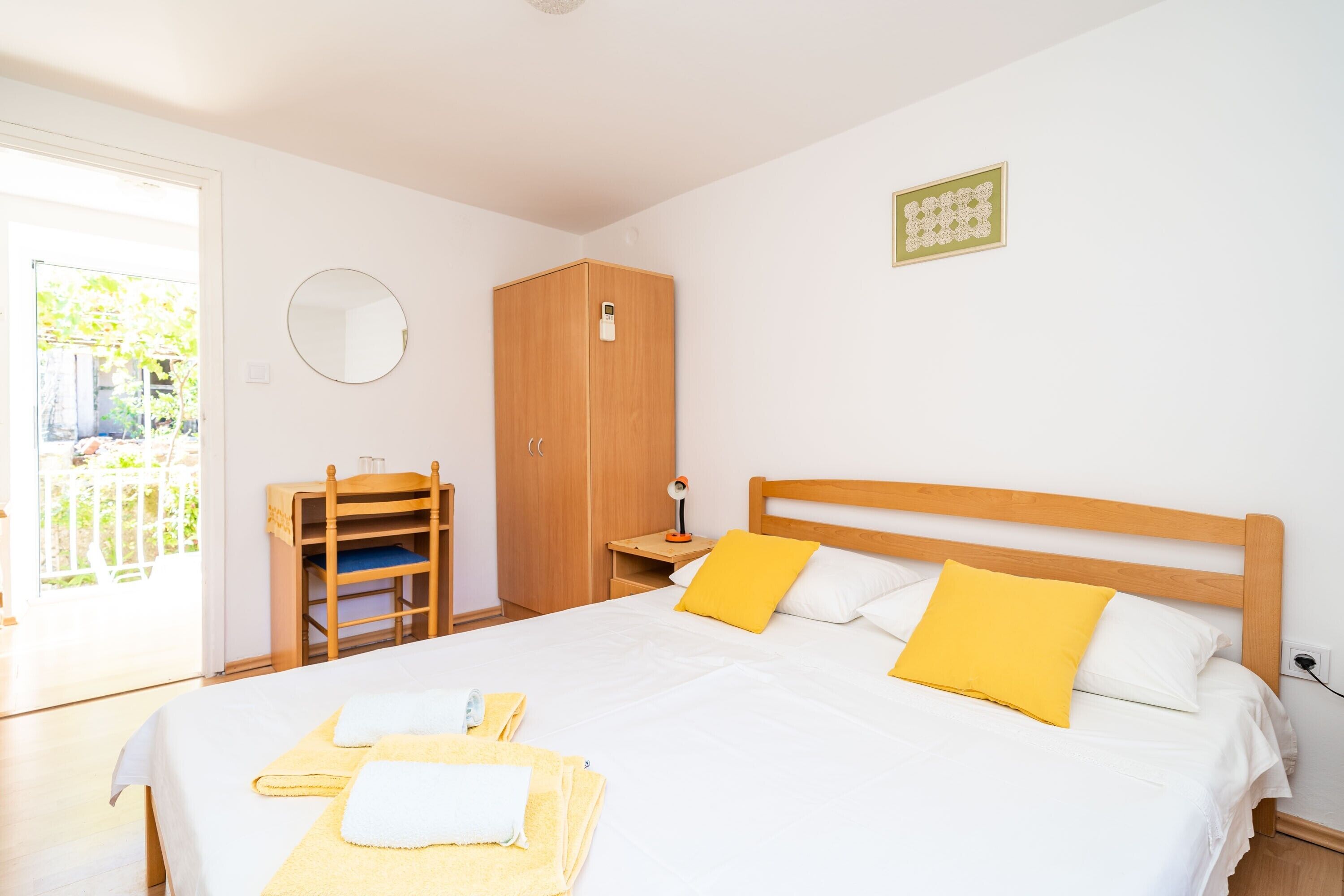 Un dormitorio con cama, armario, escritorio y espejo.