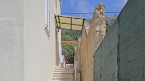 Una escalera conduce a un edificio de fachada blanca y pared con malla verde.