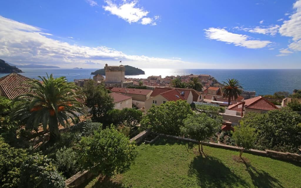 A coastal town with traditional architecture, a prominent tower, and a view of the sea.
