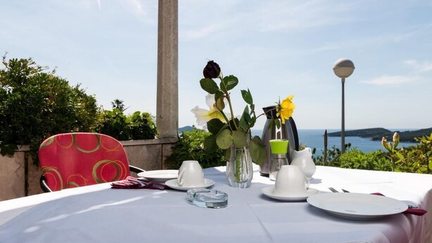 Ein Tisch für zwei, gedeckt mit weißen Tischdecken, eine Vase mit Blumen und Meerblick.