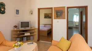 Ett kompakt bostadsutrymme med en tv, en säng och en matplats som syns genom en öppen dörr.