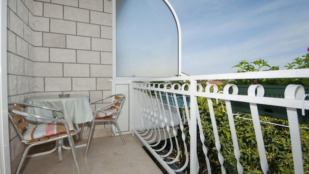 Un balcone con ringhiera bianca, un tavolino e due sedie.