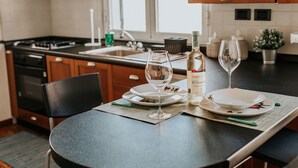 A kitchen with a dining table set for two, featuring a bottle of wine, two wine glasses, and a placemat. - La Vivagna - Sea view house among the olive trees (Leivi)
