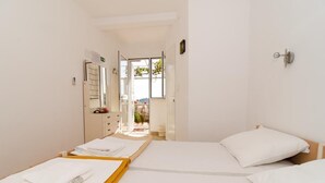 Habitación de hotel con dos camas, baño con ducha y vistas al exterior.