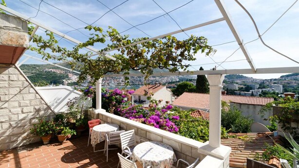 Una terraza con pérgola, mobiliario exterior y vistas a un paisaje urbano.