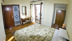 Ein Schlafzimmer mit Bett, Schreibtisch, Stuhl, Waschbecken und Kleiderschrank.
