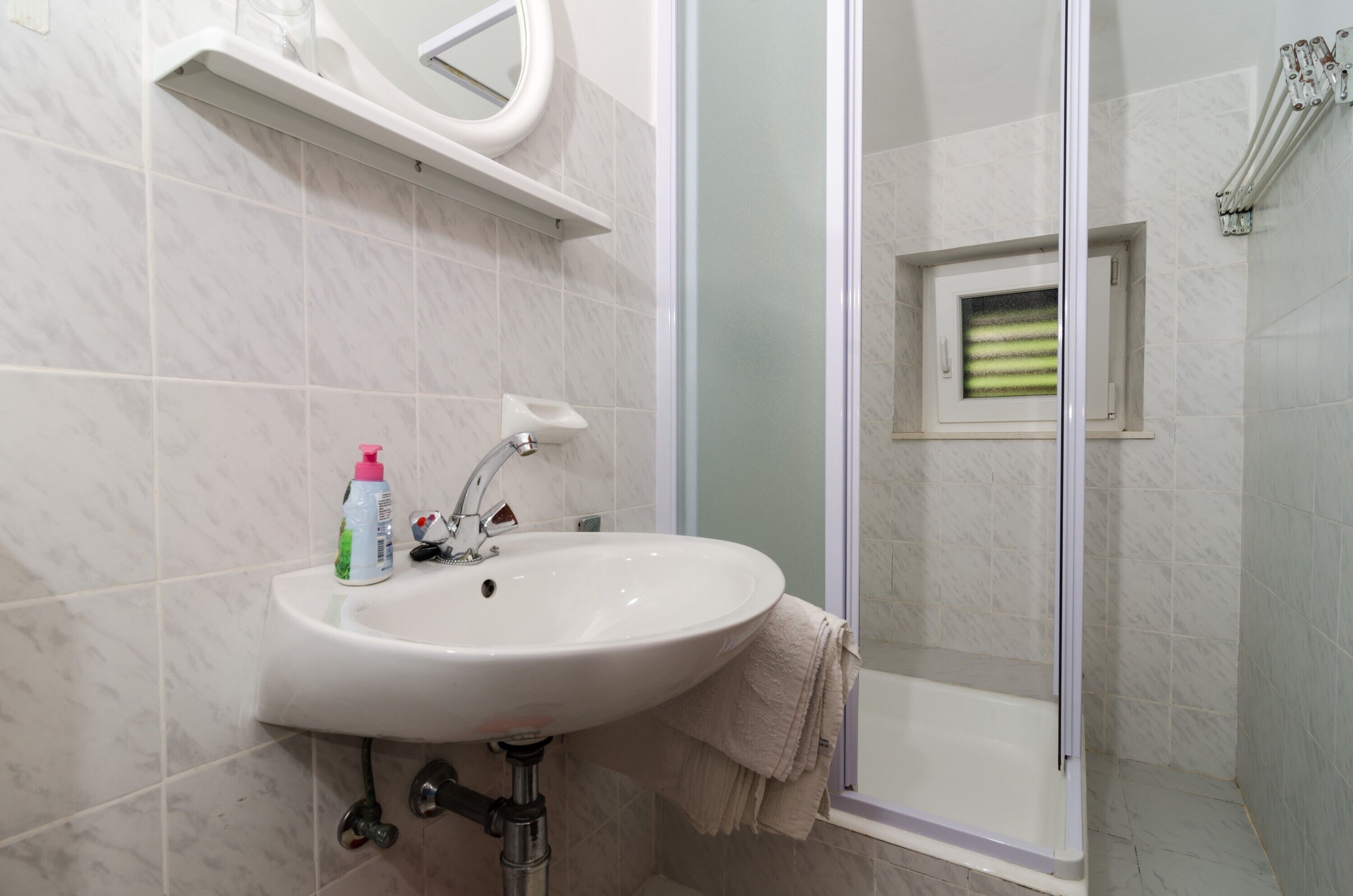 A bathroom with a white sink, a mirror, and a glass-enclosed shower.