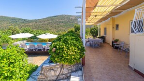 A patio area with a pool, outdoor furniture, and a view of a hill.