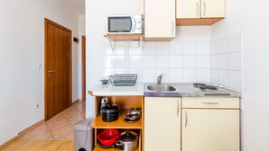 Une cuisine de taille réduite, équipée d’un four à micro-ondes, d’un évier et de meubles de rangement en bois.