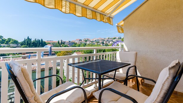 Un balcon avec une table et des chaises, donnant sur un paysage urbain.