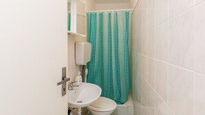 Un baño con inodoro, lavamanos y cortina de ducha verde con lunares.