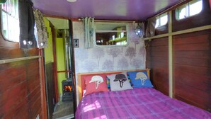 A bedroom with a bed, a window, a door, and a small heater. - Rumenco, self contained 2 person, secluded/unique off grid glamping, own meadow! (boncath)