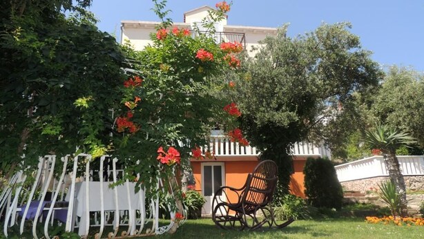 A garden with a white fence, a chair, and a building with a balcony.